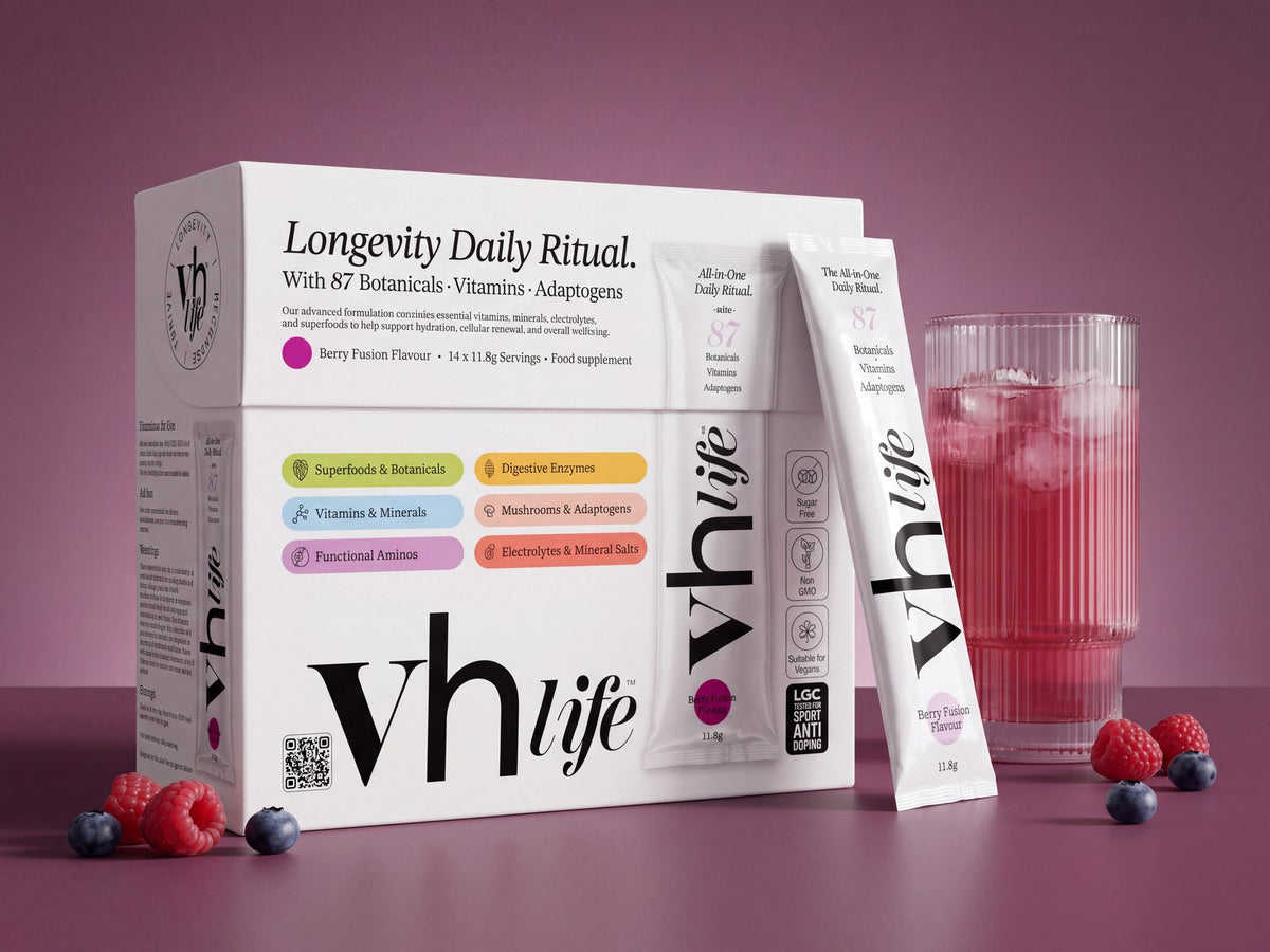 The VH Life box with a sachet, a glass of the berry drink and berries on a plum surface