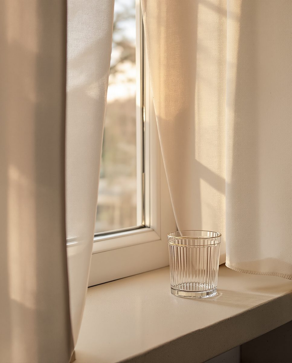 A windowsill at dawn with a ribbed glass in soft light